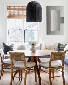 a dining room table with chairs and a bowl of fruit on it's centerpiece