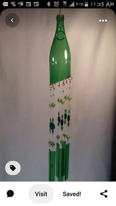 a green bottle hanging from the side of a white wall next to earrings and necklaces