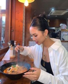 a woman is cooking in a pan on the counter at a restaurant with her spoon and knife