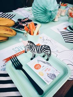 a zebra figurine sitting on top of a plate next to a fork and knife