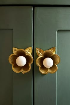 an egg is sitting in the center of a golden flower on a green door handle