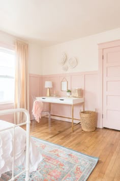 a bedroom with pink walls and wooden floors, white furniture and rugs on the floor