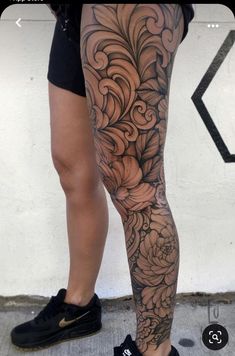 a woman's legs with tattoos on them and flowers in the middle of her leg