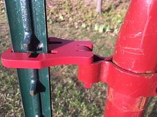 a red and green fire hydrant sitting on top of a grass covered field next to a fence