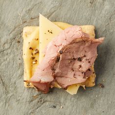 a piece of meat and cheese sitting on top of a stone slab covered in dirt