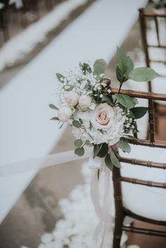 a bouquet of flowers sitting on top of a wooden chair next to another white chair