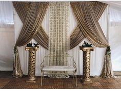 a white bench sitting next to two gold vases on top of a wooden floor