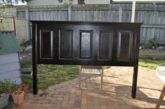 a wooden bed frame sitting on top of a brick patio