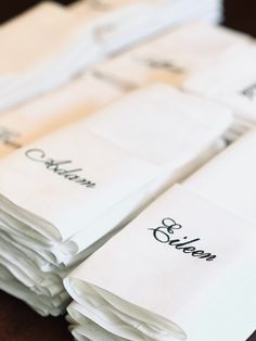 a stack of folded white napkins sitting on top of a wooden table next to each other