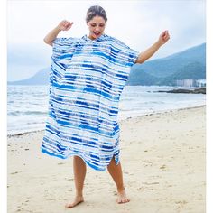 a woman standing on top of a beach covered in a blue and white cover over her body