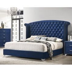 a blue bed sitting in a bedroom next to a night stand and chest of drawers