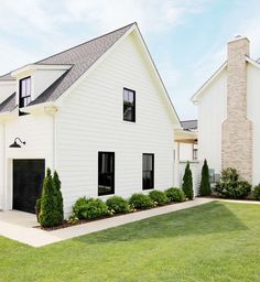 a large white house with black doors and windows on the side of it's front lawn