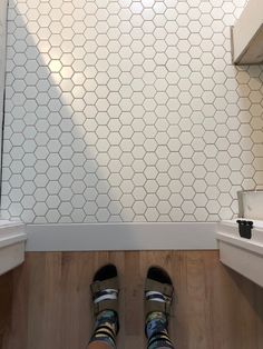 someone's feet are standing on the floor in front of a tiled shower stall