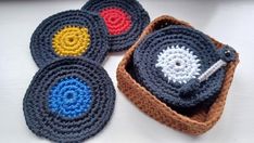 four crocheted coasters in a basket on top of a white countertop