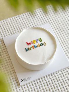 a white cake with the words happy birthday on it sitting on top of a card