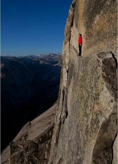 a man standing on the side of a mountain next to a red shirted person