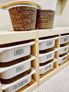 two baskets sitting on top of wooden shelves filled with white containers and labeled labels that read cards, tools, coloring