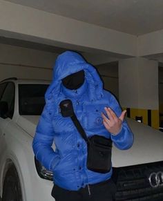 a man in a blue jacket standing next to a white car