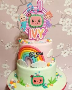 there is a three layer cake decorated with animals and rainbows on the top tier