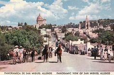 people are riding horses down the street in front of an old town with tall buildings