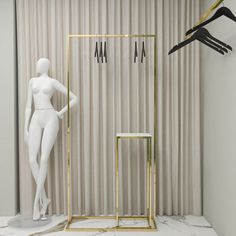 a white mannequin standing next to a gold frame