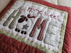 a close up of a pillow on a bed with the words home sweet and a sheep