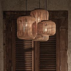 three lights hanging from the ceiling in front of wooden shutters