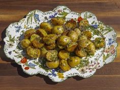 a white plate topped with potatoes covered in seasoning on top of a wooden table