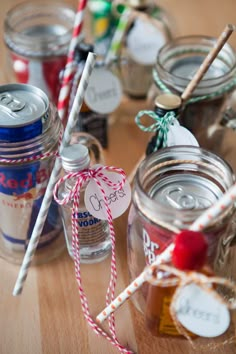 mason jars filled with candy and drinks on top of a wooden table next to twine lollipop sticks