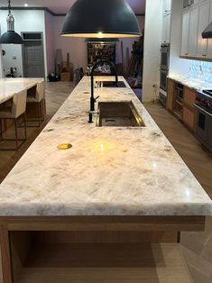 a large kitchen island with a sink and lights hanging from it's ceiling over the counter