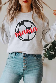 a woman wearing a sweatshirt with the word mama printed on it and holding her hair in front of her face