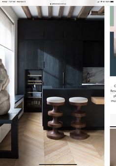 a kitchen with black cabinets and stools in it