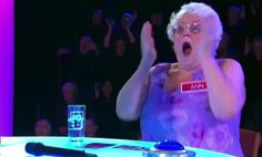 an older woman with her hands in the air while sitting at a table and clapping