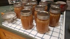 there are many mason jars on the kitchen counter with spoons and measuring cups next to them