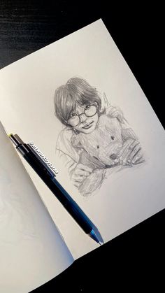 a pencil drawing of a boy with glasses holding a teddy bear on top of a piece of paper