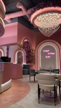 the interior of a restaurant with pink walls and chandeliers