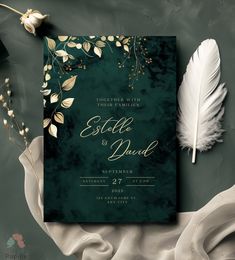 a green wedding card with gold foil on it and a white feather next to it