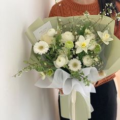 a woman holding a bouquet of white flowers