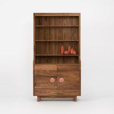 a wooden bookcase with two pink vases on top