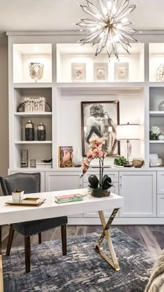 a living room filled with furniture and a chandelier hanging from the ceiling over a white table