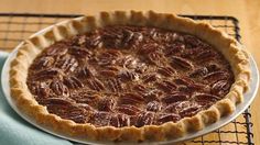 a pecan pie sitting on top of a cooling rack next to a blue napkin