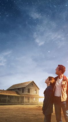 two people standing in front of a house under the stars