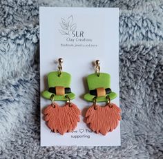 two pairs of green, orange and pink earrings on top of a white card board