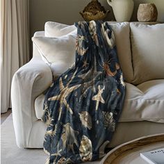 a living room with a white couch covered in a blue sea creature print throw blanket