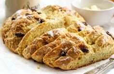 some type of bread with raisins on it next to a cup and spoon