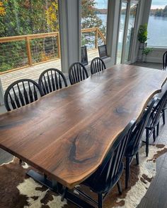 a large wooden table sitting in the middle of a living room next to a window