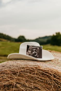 a white cowboy hat sitting on top of a hay bale in the middle of a field