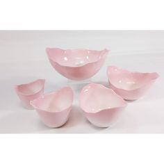 four pink bowls sitting next to each other on a white surface