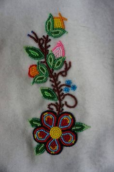 a close up of an embroidered object on a white cloth with flowers and leaves in the center