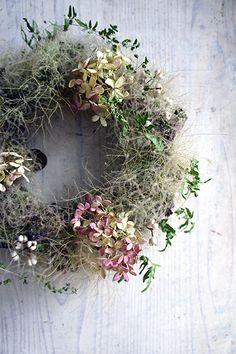 an overhead view of a wreath with flowers and plants in it on a wooden surface